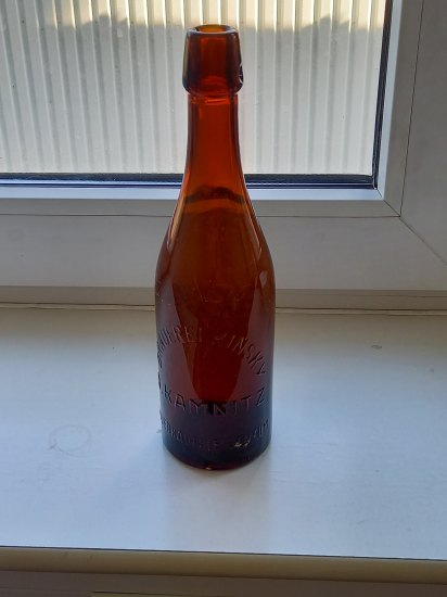 Pivní láhev s embosovaným nápisem.