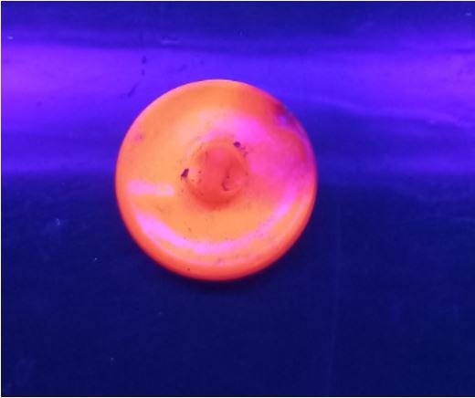 Knoflík zářící červeně v UV světle.